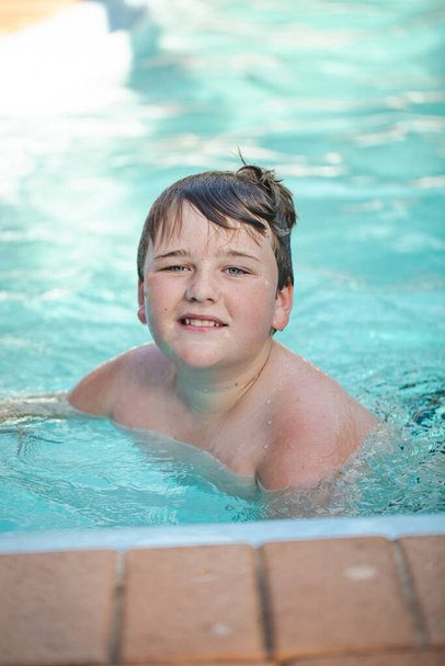 Счастливый мальчик дошкольного возраста плавает в бассейне во дворе - Фото, изображение