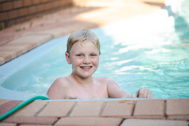 Happy pre teen boy swimming in backyard pool - Photo, Image