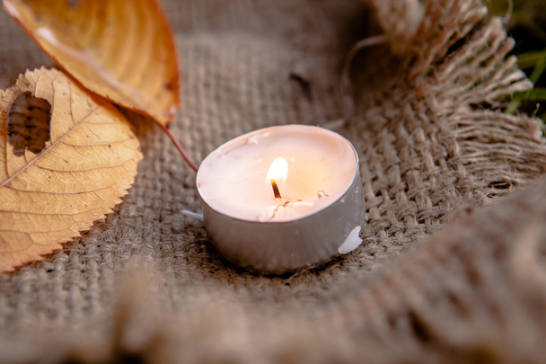 Сухие кленовые листья и теплый свет свечи
 - Фото, изображение