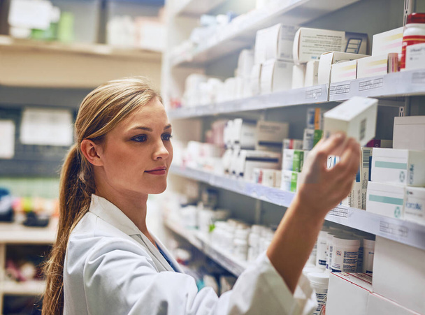 Je sais exactement quel médicament vous aidera. Prise de vue d'un pharmacien regardant des médicaments sur une étagère. - Photo, image