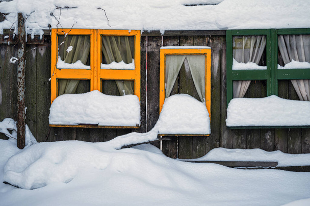 snow-covered colorful window frames by a wooden fence, decorations in the childrens playground - Foto, immagini