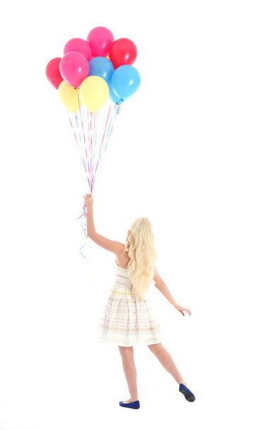 Full length portrait of blonde girl wearing party dress, holding bunch of colourful balloons. Isolated on white studio background - Φωτογραφία, εικόνα
