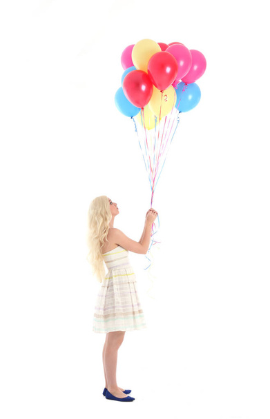 Full length portrait of blonde girl wearing party dress, holding bunch of colourful balloons. Isolated on white studio background - 写真・画像