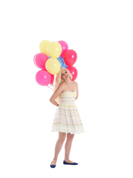 Full length portrait of blonde girl wearing party dress, holding bunch of colourful balloons. Isolated on white studio background - Photo, Image