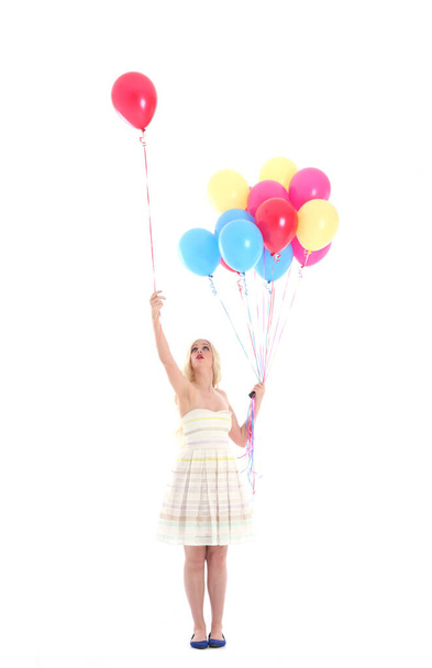 Full length portret van blond meisje dragen feestjurk, met een bos van kleurrijke ballonnen. Geïsoleerd op witte studio achtergrond - Foto, afbeelding