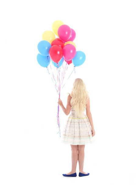 Full length portrait of blonde girl wearing party dress, holding bunch of colourful balloons. Isolated on white studio background - Фото, изображение
