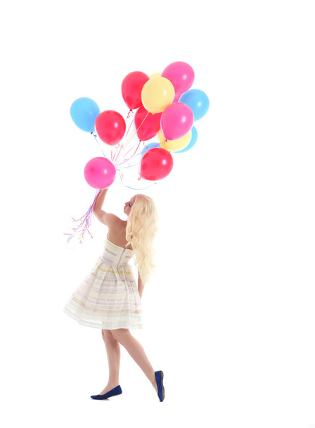 Full length portrait of blonde girl wearing party dress, holding bunch of colourful balloons. Isolated on white studio background - Photo, image