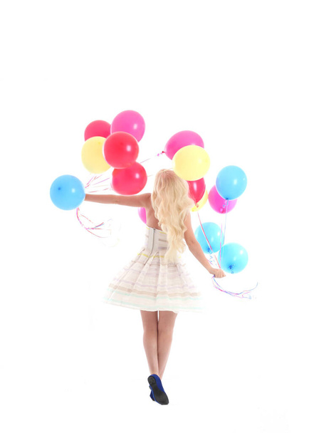Dlouhý portrét blondýnky, oblečené do společenských šatů, držící hromadu barevných balónků. Izolováno na bílém pozadí studia - Fotografie, Obrázek