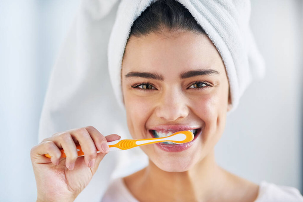 Oral hygiene comes first. Portrait of a beautiful young woman brushing her teeth in the bathroom at home. - Photo, image