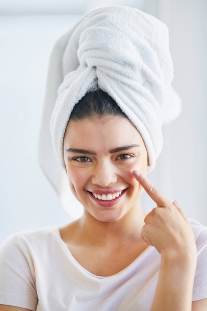 Give your skin the moisture it needs. Portrait of a beautiful young woman applying moisturizer to her skin in the bathroom at home. - Φωτογραφία, εικόνα
