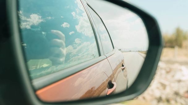 Passenger riding in car and taking photo from window on a road trip - 写真・画像