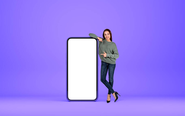Young woman smiling, full length. Smartphone mock up copy space screen, purple violet background. Concept of new mobile app recommending. 3D rendering - Foto, immagini