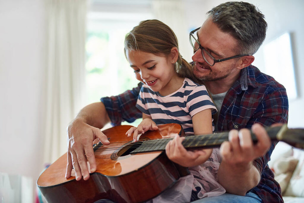Tu es si douée pour ça... Tourné d'une petite fille jouant de la guitare avec son père. - Photo, image