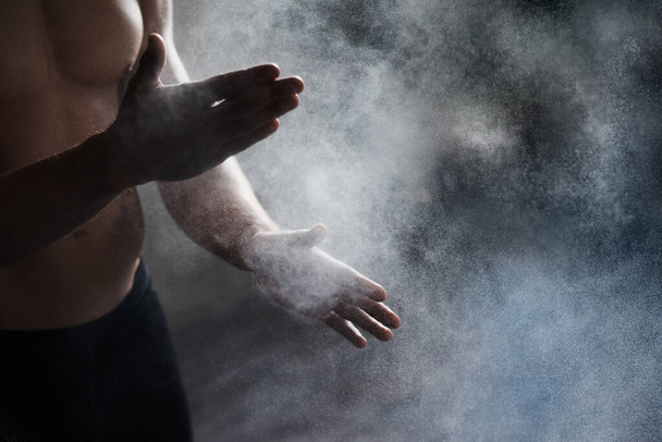 Getting ready to perform. A cropped view of a male gymnast dusting his hands with chalk. - Foto, Bild