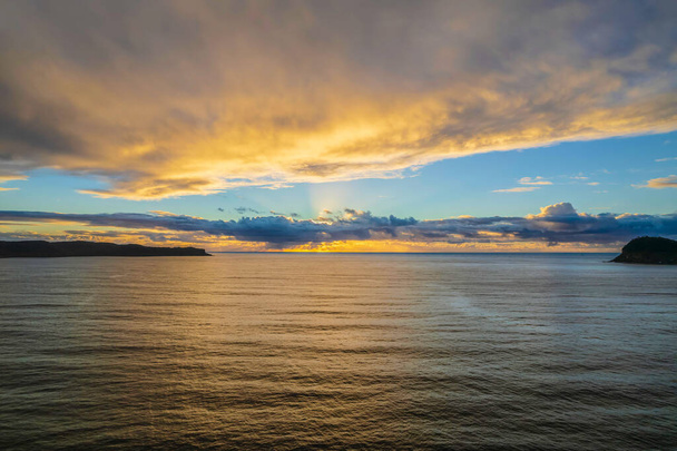 オーストラリア、ニューサウスウェールズ州中央海岸のパールビーチで大気と雲に覆われた日の出. - 写真・画像