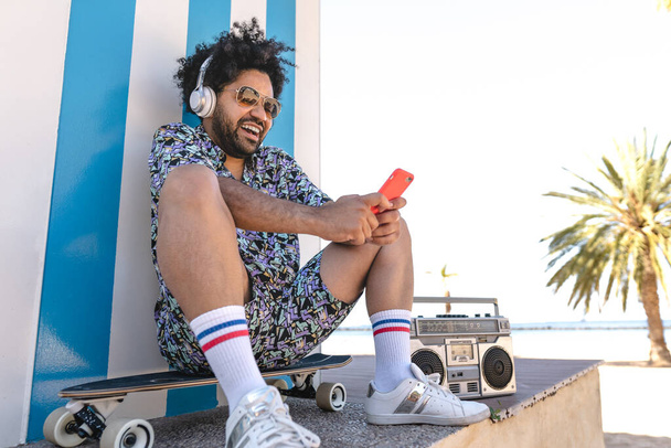 Spanyol férfi szórakozás használ mobil okostelefon és zenét hallgatni a trópusi strandon - Fotó, kép