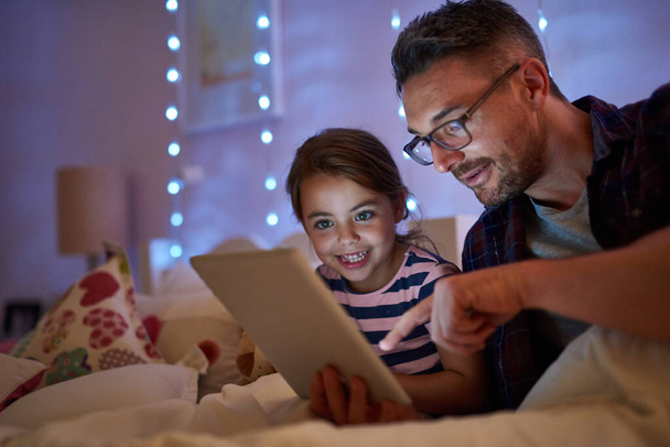 Verás, vivieron felices para siempre. Foto de una niña y su padre usando una tableta antes de acostarse. - Foto, imagen