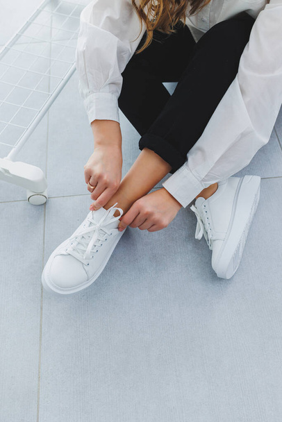 Gambe donna in pantaloni neri e sneakers in pelle bianca. Stile casual moderno. Nuova collezione di scarpe - Foto, immagini