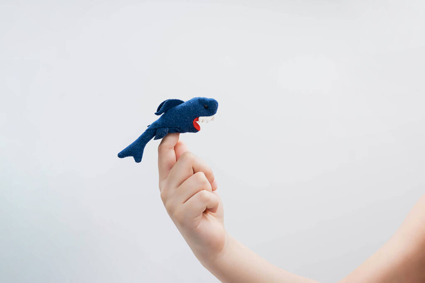 Jongen speelt vinger speelgoed figuur van dier. Haaien figuur om vinger van kind hand, poppentheater. - Foto, afbeelding