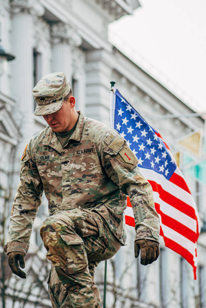 Vilnius, Lituania - 16 de febrero de 2022: Soldado del Cuerpo de Marines de los Estados Unidos en la parte superior de un vehículo militar con bandera estadounidense, ejército de los Estados Unidos o de los Estados Unidos listo para el entrenamiento o la guerra, vertical - Foto, Imagen