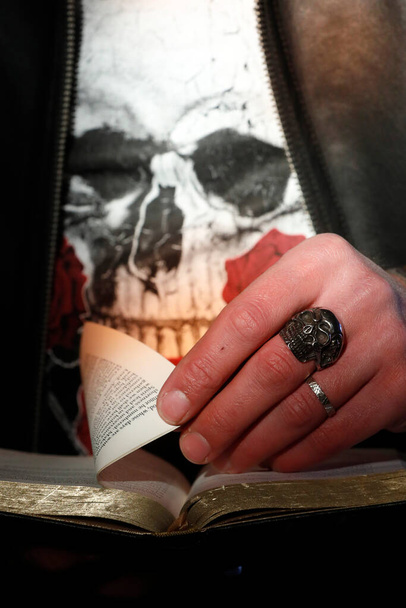Ο άνθρωπος με το δαχτυλίδι κρανίο διαβάζει την Αγία Γραφή. Γαλλία. - Φωτογραφία, εικόνα