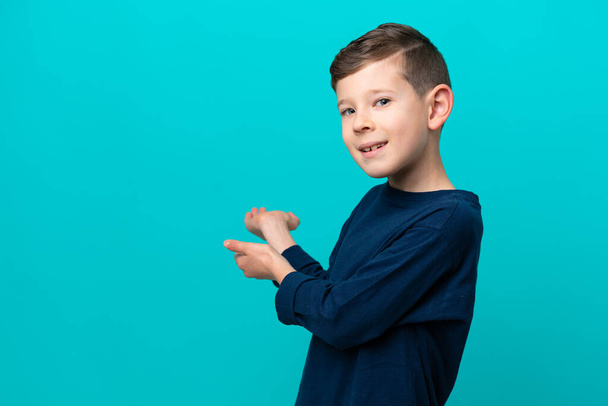 Μικρό αγόρι απομονωμένο σε μπλε φόντο απλώνει τα χέρια στο πλάι για την πρόσκληση να έρθει - Φωτογραφία, εικόνα