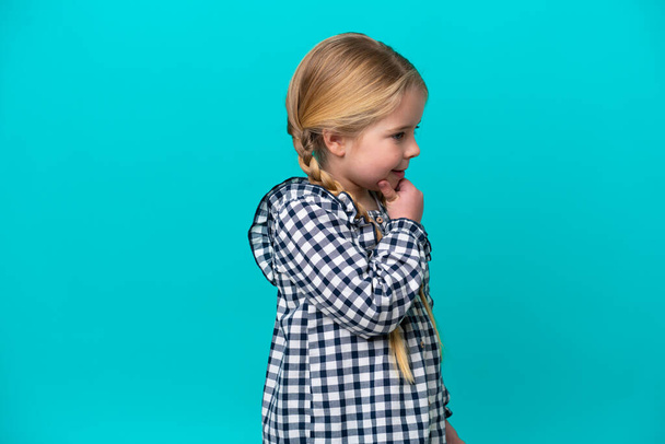 Μικρή καυκάσια κοπέλα απομονωμένη σε μπλε φόντο αναζητούν πλευρά - Φωτογραφία, εικόνα