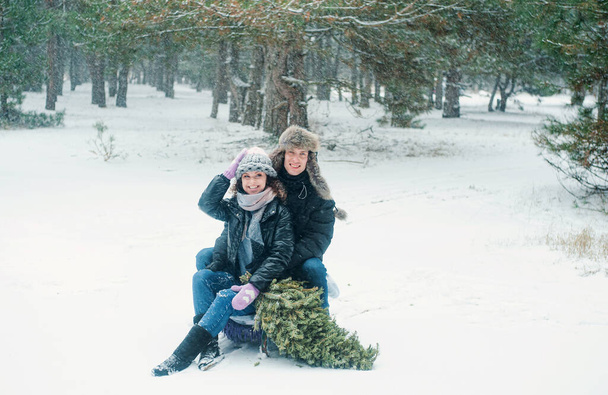Жінка і чоловік ходять в зимовому лісі. Щаслива пара тримає соснове дерево розважається зі снігом
. - Фото, зображення