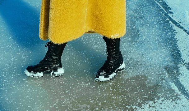 Young running woman in yellow coat walking on snowy ice.  - 写真・画像