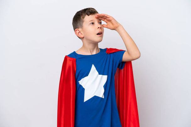 Super hrdina malý chlapec izolovaný na bílém pozadí dělá překvapení gesto při pohledu na stranu - Fotografie, Obrázek