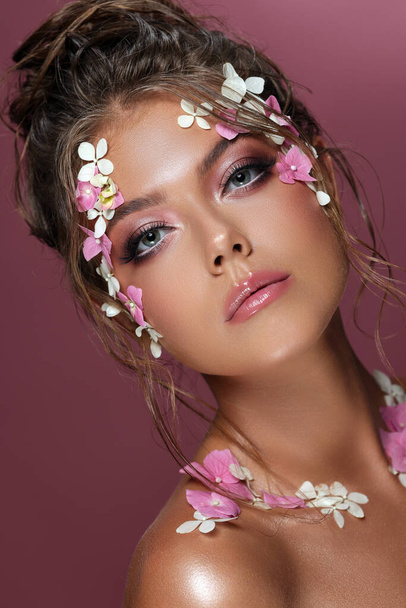 Beautiful caucasian woman with flowers on pink background. - Фото, зображення