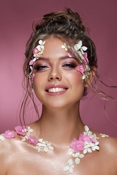 Beautiful caucasian woman with flowers on pink background. - Φωτογραφία, εικόνα