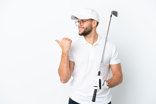 白い背景に孤立したゴルフをして製品を提示する側を指しているハンサムな若い男 - 写真・画像