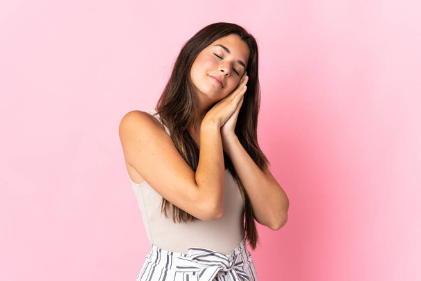 Young brazilian woman isolated on pink background making sleep gesture in dorable expression - Photo, Image