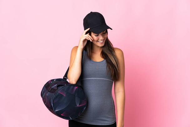 Young sport brazilian girl with sport bag isolated on pink background laughing - Foto, Imagem