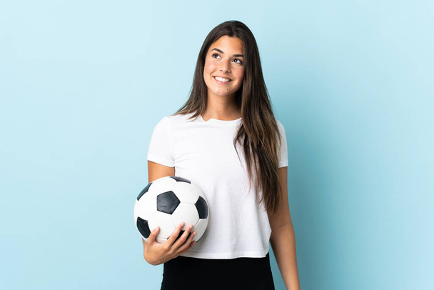 Jeune joueur de football brésilien fille isolée sur fond bleu penser une idée tout en levant les yeux - Photo, image