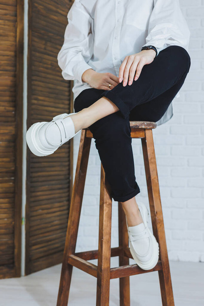 Nogi młodej pięknej kobiety w czarnych spodniach i nowoczesnych stylowych białych skórzanych mokasynach. Nowa kolekcja damskich butów wiosna-lato 2022 roku - Zdjęcie, obraz