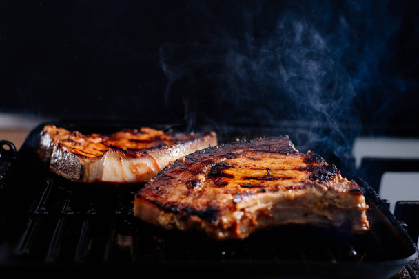 Pork rib steak in sauce and spices fried in a grill pan. The process of cooking pork steak. - Zdjęcie, obraz