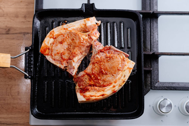Bifteck de côtes de porc en sauce et épices frites dans une poêle à griller. Le processus de cuisson du steak de porc. - Photo, image