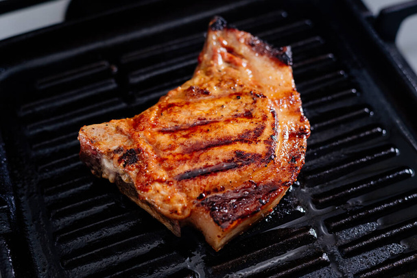 Pork rib steak in sauce and spices fried in a grill pan. The process of cooking pork steak. - Foto, Imagem