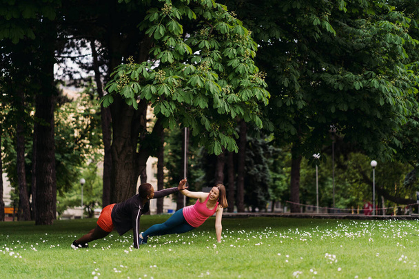 Две красивые женщины делают доски на городской площади во время занятий спортом - Фото, изображение