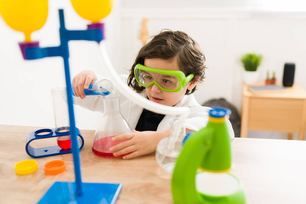 Красива дитина в лабораторному пальто і захисні окуляри дізнається про хімію, граючи як вчений
 - Фото, зображення