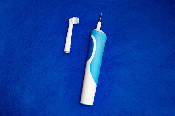 Cepillo de dientes eléctrico moderno sobre fondo azul. Herramienta controlada para el cuidado bucal diario. - Foto, Imagen