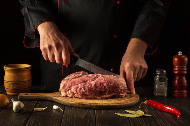 Cocinar carne fresca cruda en la cocina por el chef. Cortar la carne con un cuchillo antes de la barbacoa. Receta para un restaurante u hotel - Foto, Imagen