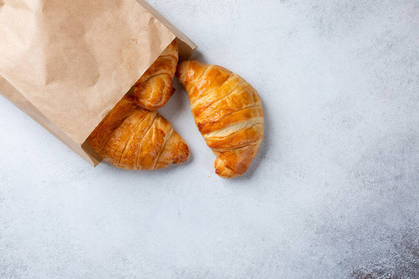 Croissants in paper bag on concrete background. Top view, copy space. - Photo, Image