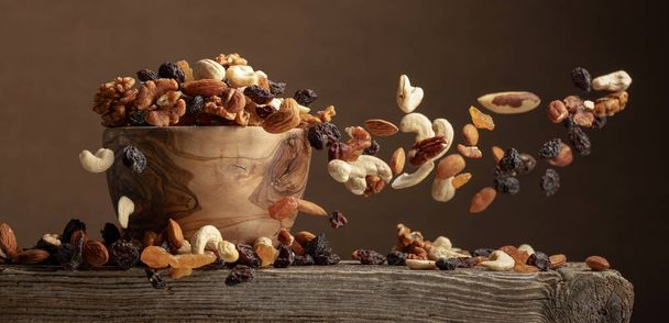 Voler des fruits secs et des noix. Le mélange de noix et de raisins secs dans un bol en bois. - Photo, image