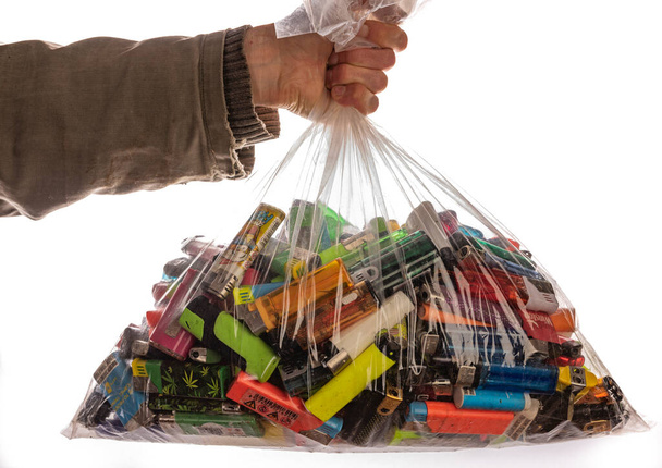 Hand with transparent sack with many color lighters - 写真・画像