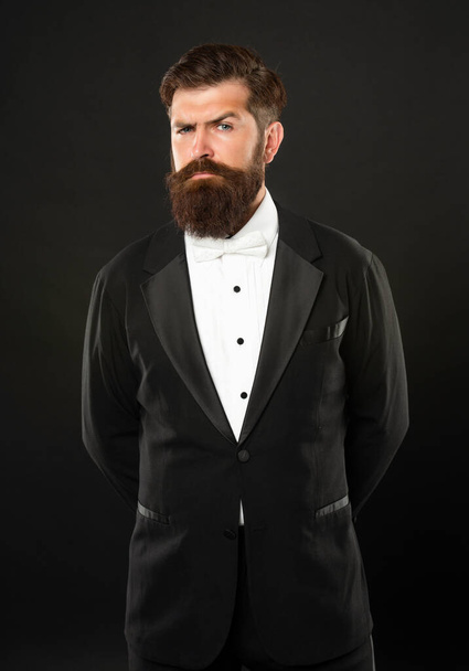 elegant butler in tuxedo on black background, formalwear - Foto, afbeelding