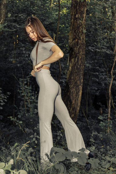 Schöne sexy brünette Mädchen posiert an einem sonnigen Sommertag am Baum im Wald. Frau mit perfektem Körper posiert auf ästhetischem Foto. - Foto, Bild