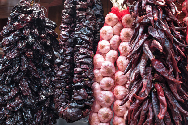 Bundles of dry garlic and hot peppers in the market of Barcelona. - Φωτογραφία, εικόνα